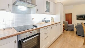 Una cocina moderna con armarios blancos, una campana extractora de acero inoxidable y un horno integrado.