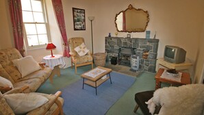 Ein gemütliches Wohnzimmer mit Kamin, Fernseher und einer bequemen Sitzecke.