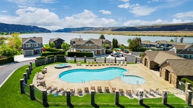 A residential area with a swimming pool surrounded by lounge chairs and a view of a lake and mountains. - Watershed Condo near Large pool/hot tub. Gorge Amp shuttle nearby book separate. (Quincy)