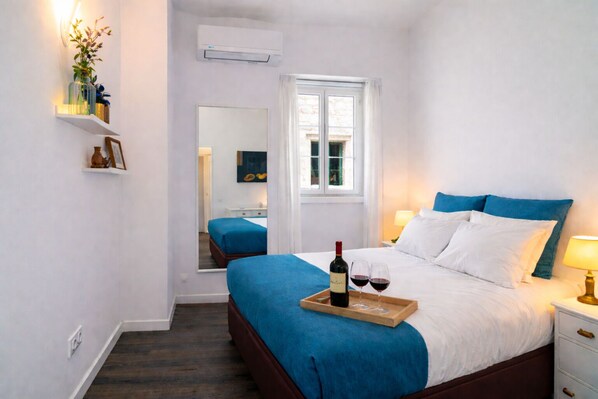 A hotel room with a bed, bedside table, and a window.