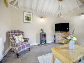 A living room with a plaid armchair, a fireplace, a television, and a wooden table.