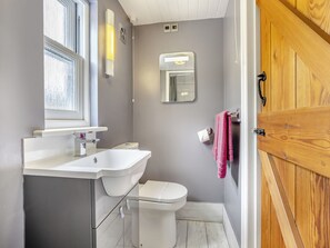 A bathroom with a white sink, toilet, and mirror.