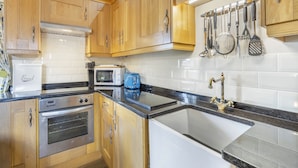 A kitchen with wooden cabinets, a built-in oven, a toaster, and a sink.