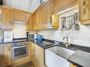 A kitchen with wooden cabinets, a built-in oven, a toaster, and a sink.
