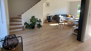 A modern living room with a staircase, a large plant, a sofa, and a coffee table.