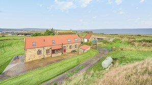 A stone building with a red-tiled roof, a grassy yard, and a view of the sea. - 2 bedroom accommodation in Whitby (Whitby)
