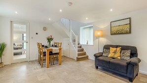 A spacious living area with a dining table set for four, a sofa, a staircase, and a painting on the wall. - 2 bedroom accommodation in Whitby (Whitby)