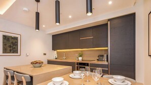 A modern kitchen with dark wood cabinets, a central island with a sink, and a dining area with a table set for four.