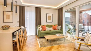 A modern living room with a green sofa, wooden chairs, a coffee table, and a dining area with a white table and chairs.