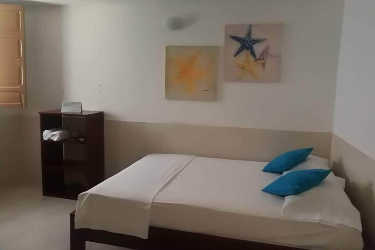 Un dormitorio con una cama, una mesita de noche y dos obras de arte en la pared.