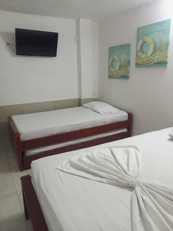 A room with two beds, a flat-screen TV mounted on the wall, and two wall art pieces.