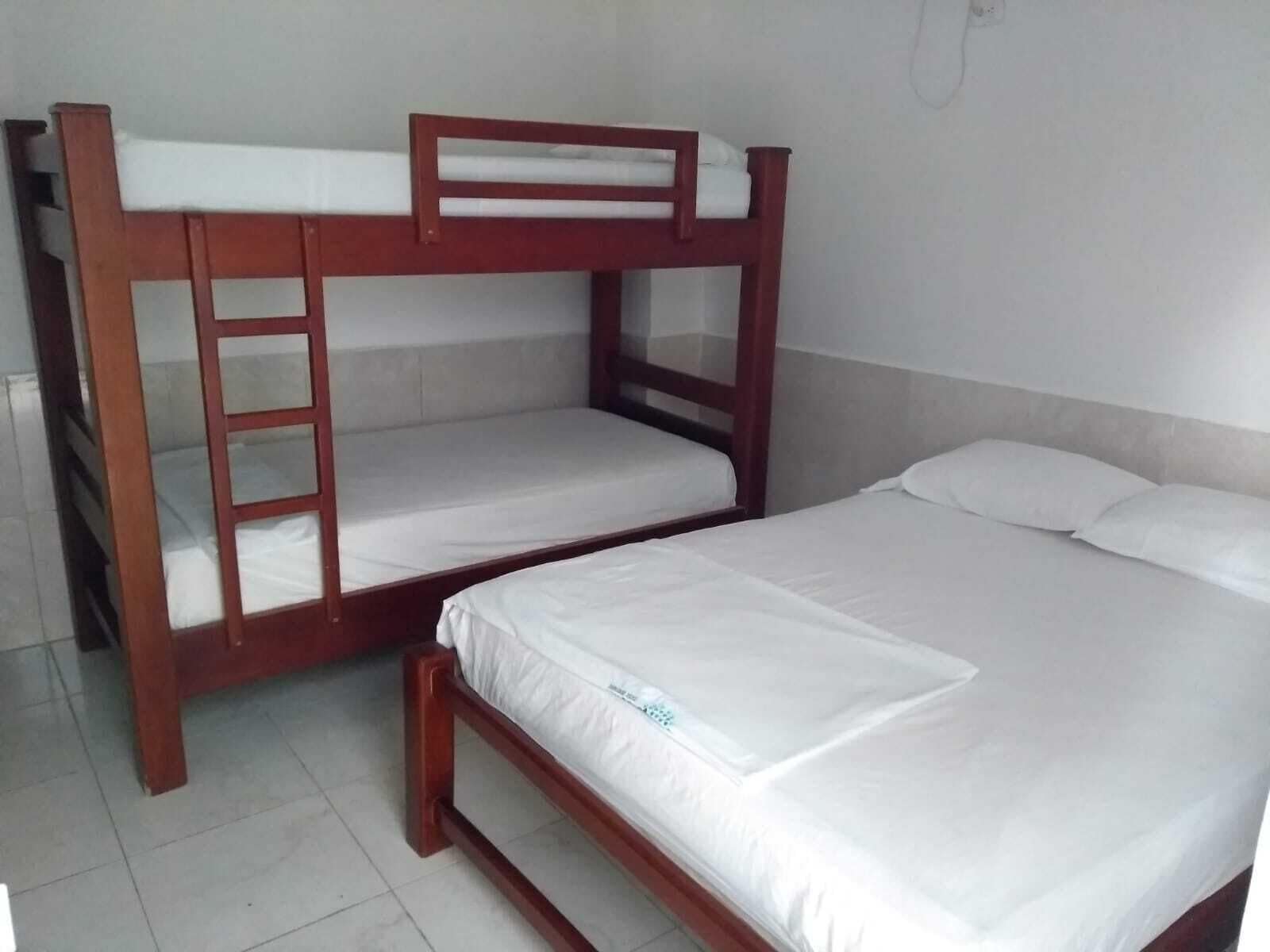 Una cama individual, una litera y un enchufe en la pared.