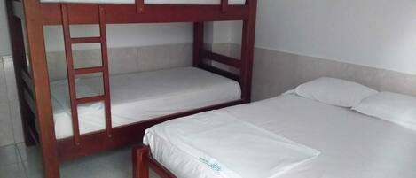 A bunk bed with a ladder, a single bed, and a wall socket.