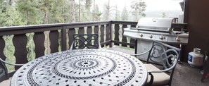 A patio with a round metal table and chairs, a grill, and a propane tank. - Family Getaway Winterpark (Winter Park)