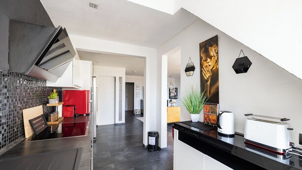 Eine moderne Küche mit schwarzem Arbeitsplatz, Edelstahlgeräten und einem roten Kühlschrank.