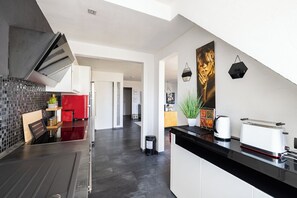 A modern kitchen with a black countertop, stainless steel appliances, and a red refrigerator.