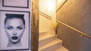Eine Treppe mit Handlauf, eine Vase mit Blumen und gerahmte Bilder an der Wand.