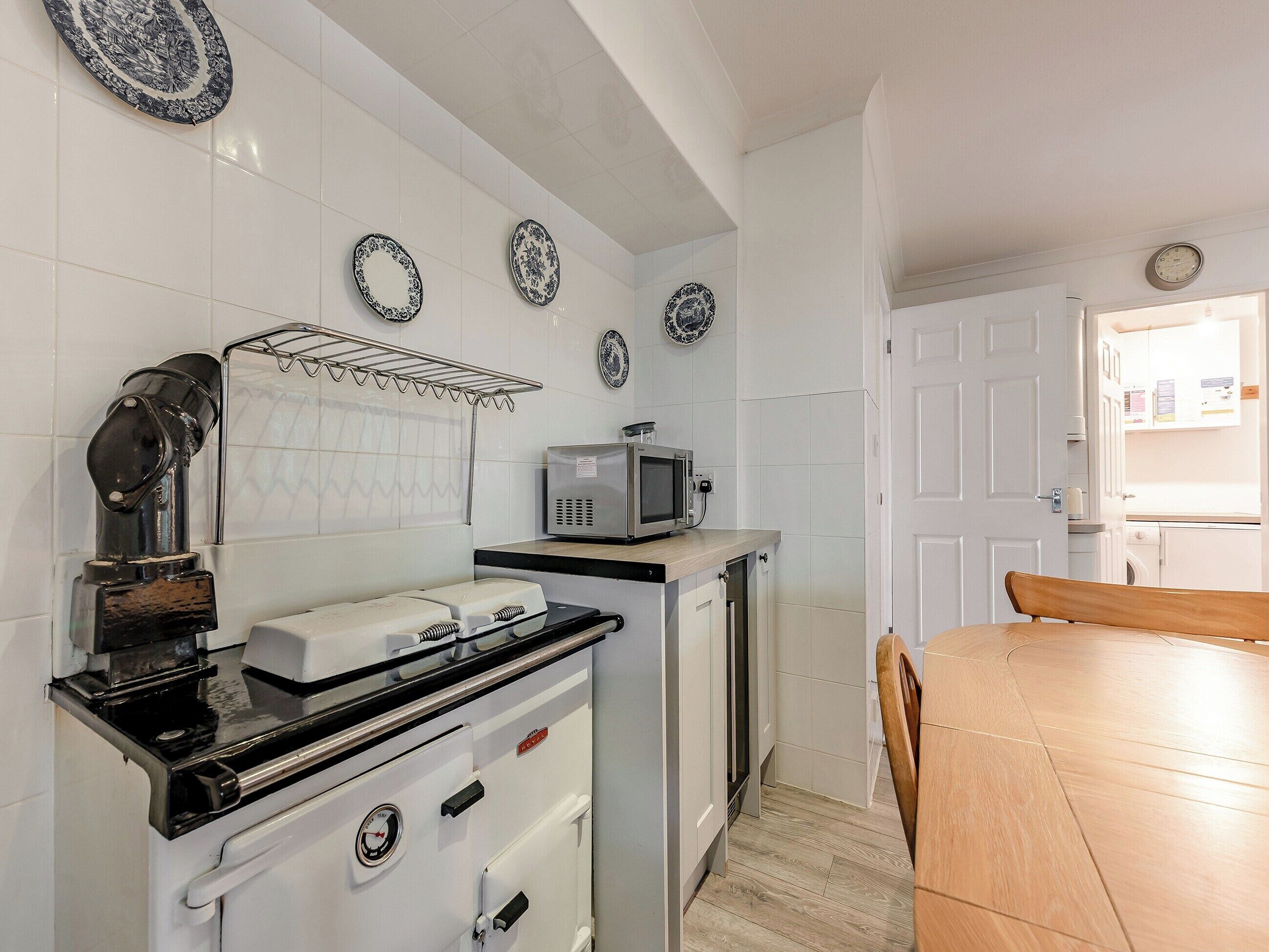 A kitchen with a stove, microwave, and cabinets. There is a dining table with chairs.
