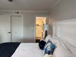 Una camera da letto con un letto, un comodino, una lampada e un bagno visibile attraverso una porta aperta.