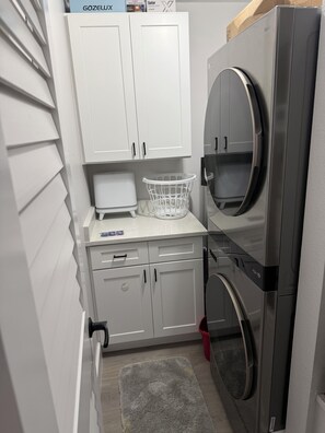 A compact laundry room with a washing machine, a dryer, and a small countertop with a basket.