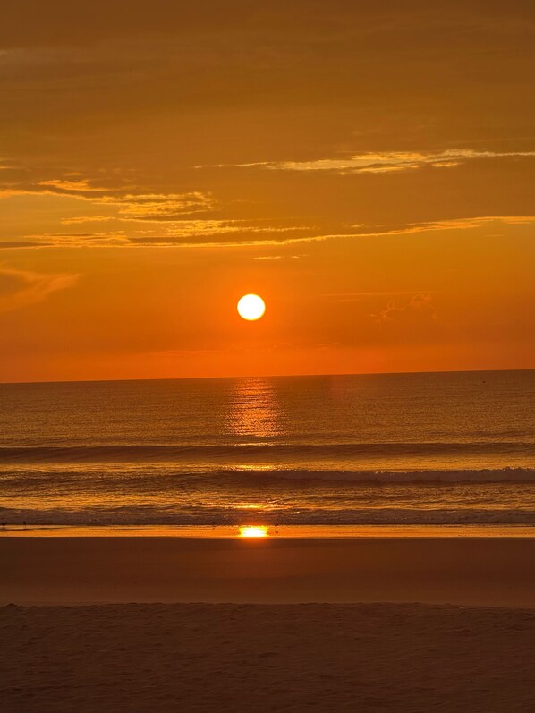 A sunset over a calm sea with a clear sky.