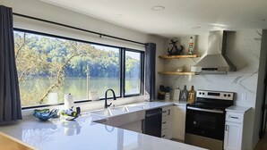 A modern kitchen with a large island, a built-in oven, and a view of a lake.