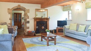 A cozy living room with a fireplace, wooden beams, and a stone archway. - 6 bedroom accommodation in Muker (Muker)