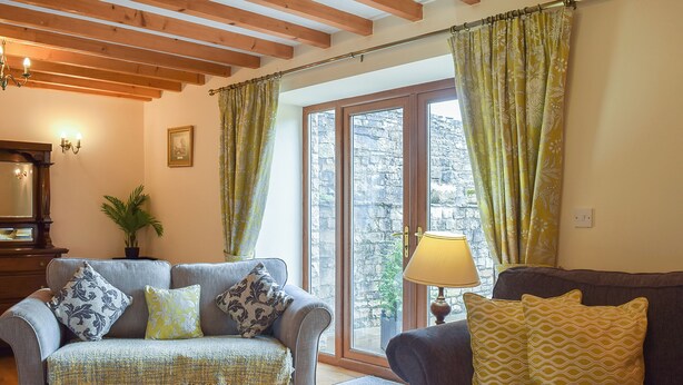 A cozy living room with two sofas, a lamp, and a large window with curtains. - 6 bedroom accommodation in Muker (Muker)