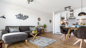 Una sala de estar moderna con un sofá gris, una mesa de centro de madera y un comedor con una mesa y sillas de madera.