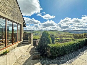 A stone building with large windows overlooking a green landscape.