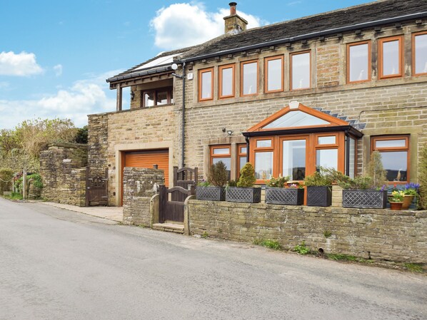 A two-story stone house with a garage, a wooden front door, and a conservatory.