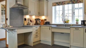 A kitchen with a granite countertop, a built-in stove, a window with a floral valance, and a sink.