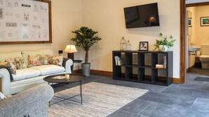 A living room with a sofa, coffee table, bookshelf, and a TV mounted on the wall.