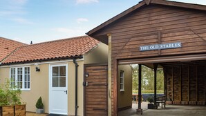 A building with a sign reading 'THE OLD STABLES' and a covered outdoor area.