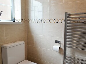 A bathroom with beige tiles, a toilet, a towel rack, and a window with a view. - An excellent base to explore the North Yorkshire Coast. (Flamborough near Bridlington)