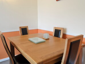 A wooden dining table with four chairs, a stack of white plates, and a decorative item on the table. - An excellent base to explore the North Yorkshire Coast. (Flamborough near Bridlington)