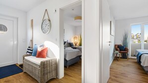 A modern, well-lit room with a wicker chair, a bed, and a view of the outside.
