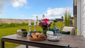 A table set outdoors with a view of a grassy field and a house in the background.