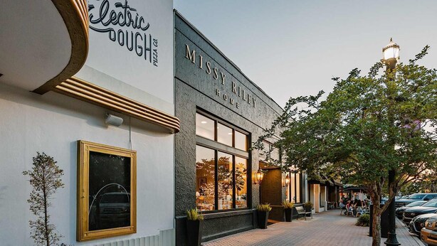 A building with a sign that reads 'Missy Riley Home' and another sign for 'Electric Dough Pizza Co.' - Renovated 2BR w/Porch & Pool Table • San Marco (Jacksonville)