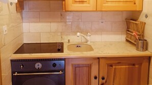 Cocina compacta con gabinetes de madera, horno empotrado, pileta y una encimera.