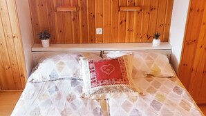 Una habitación con paneles de madera, una cama con ropa de cama estampada y un cojín decorativo.