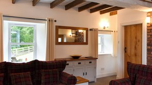 Une pièce avec un canapé à carreaux, une table en bois, un miroir, une armoire et une porte.