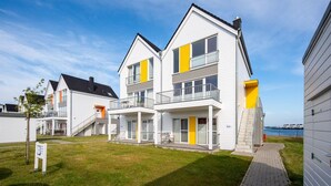 A modern residential building with a balcony, a staircase, and a view of the water. - Nice apartment in Olpenitz with sauna (Olpenitz)