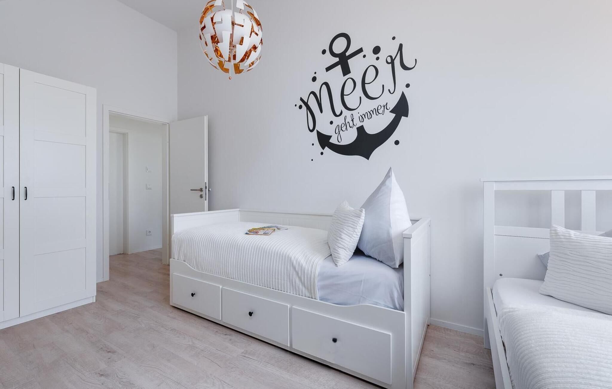 Une chambre à coucher avec un lit, une armoire blanche et un motif décoratif sur le mur.