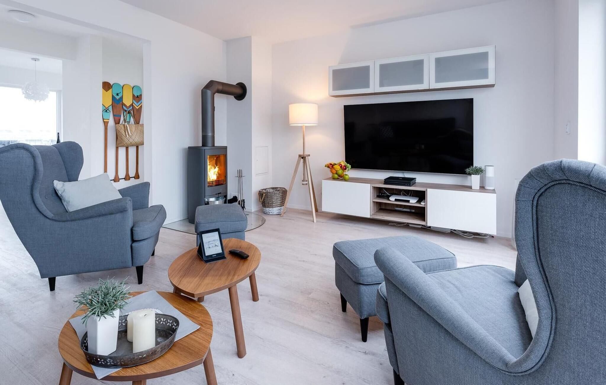 Un salon moderne avec des canapés gris, une table basse en bois, un téléviseur et un poêle à bois.