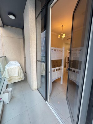 A room with bunk beds, a glass door, and a ceiling light.