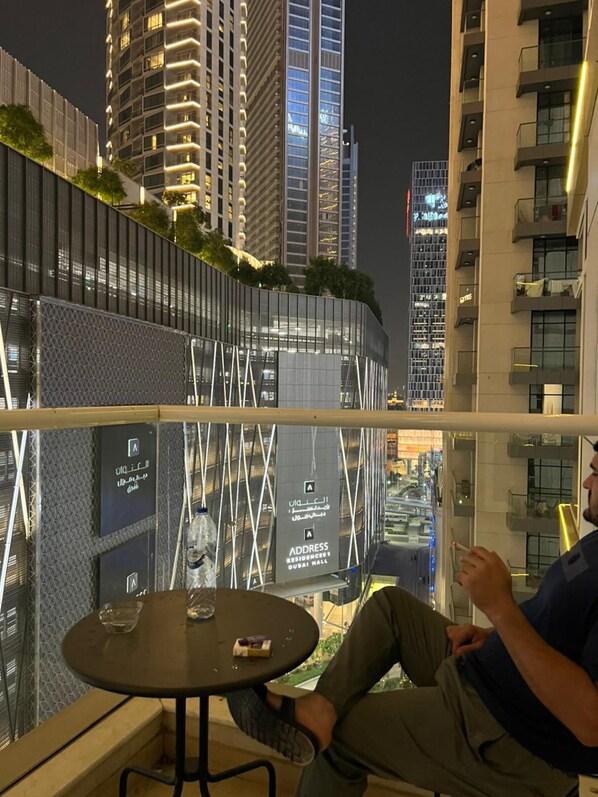 A man sitting at a table with a view of a modern building complex at night.
