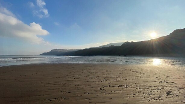 A beach with footprints in the sand, a clear sky, and the sun setting over the water. - Smugglers Rock House (Ravenscar, near Robin Hoods Bay)