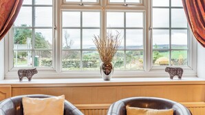 A room with a large window, two decorative animal figurines, a vase with dried plants, and two chairs with cushions. - Smugglers Rock House (Ravenscar, near Robin Hoods Bay)