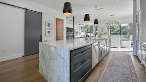 A modern kitchen with a marble island, black pendant lights, and a view to the living area. - Luxe Home in Iconic Zilker/ Barton Springs neighborhood- POOL (Austin)